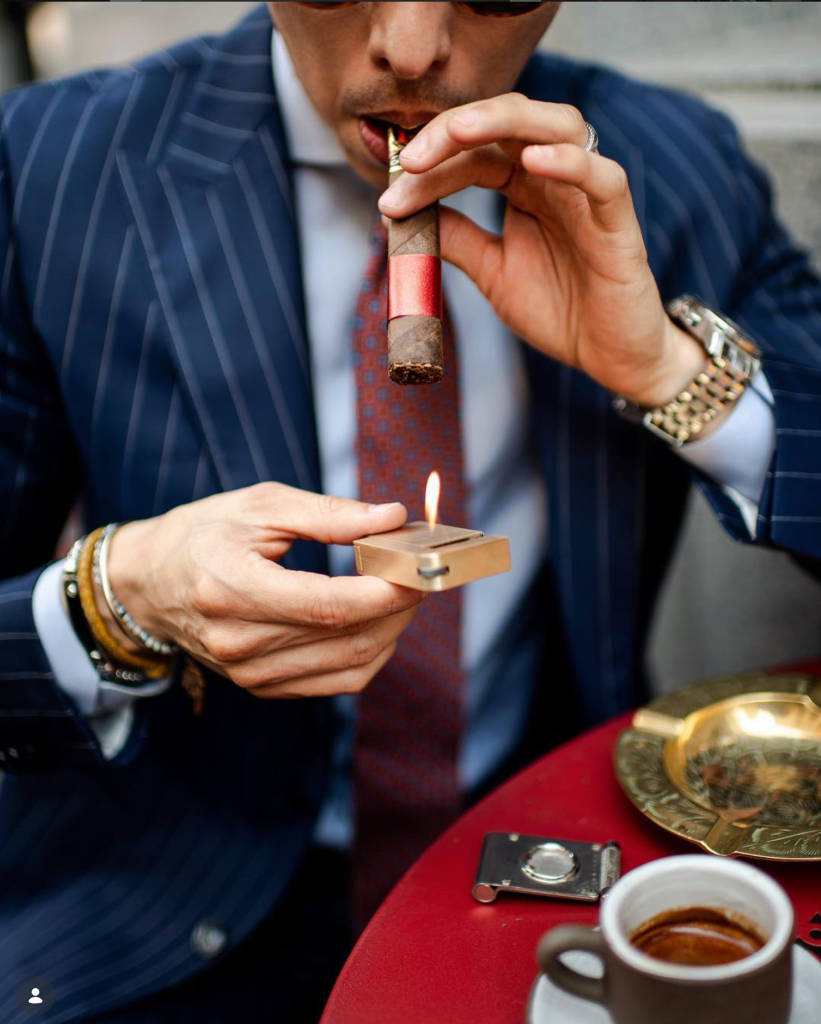 Man in pinstripe suit lighting a cigar with a KNNOX lighter