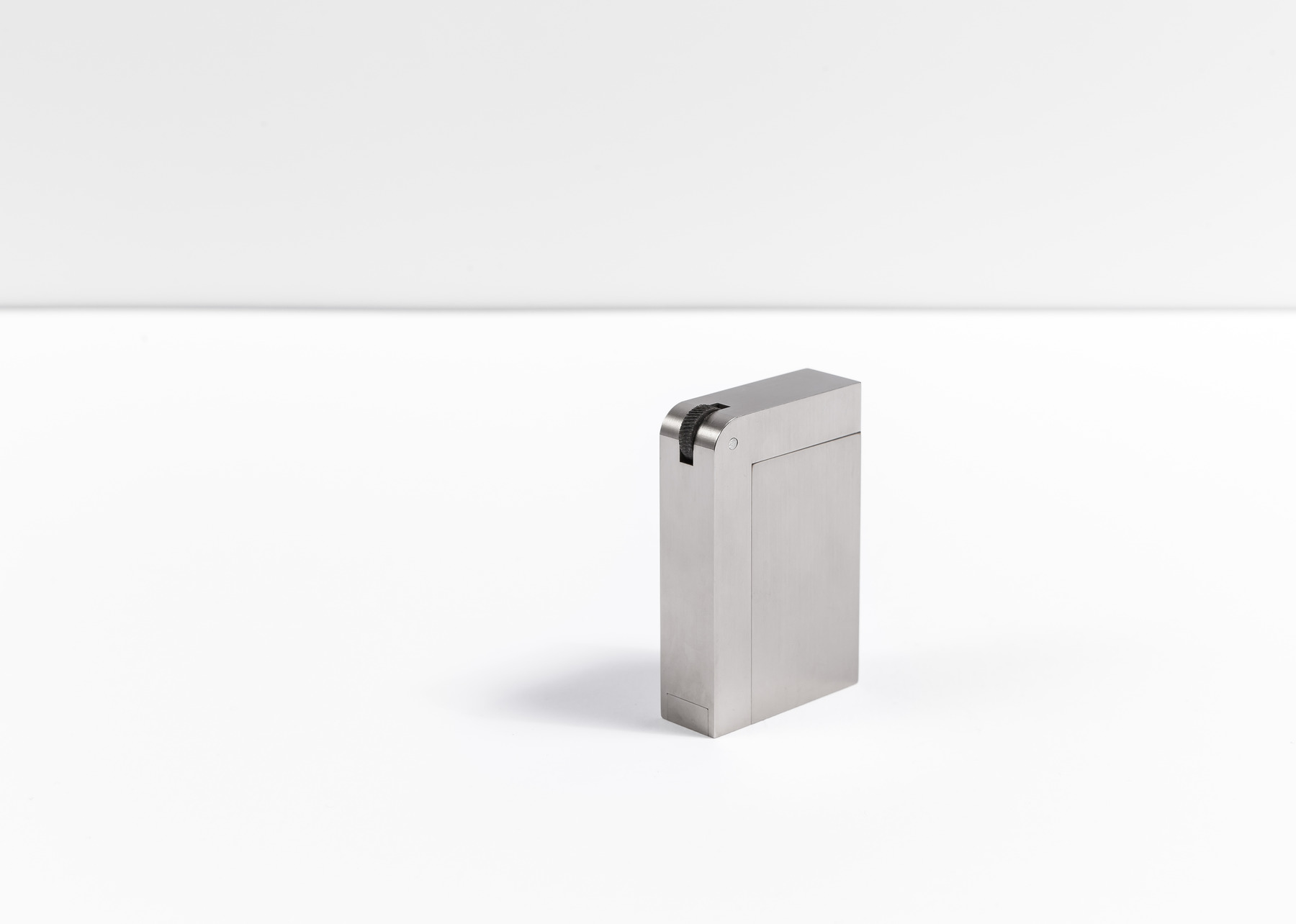 A closed silver-toned KNNOX object stands alone on a white studio surface with broad negative space.
