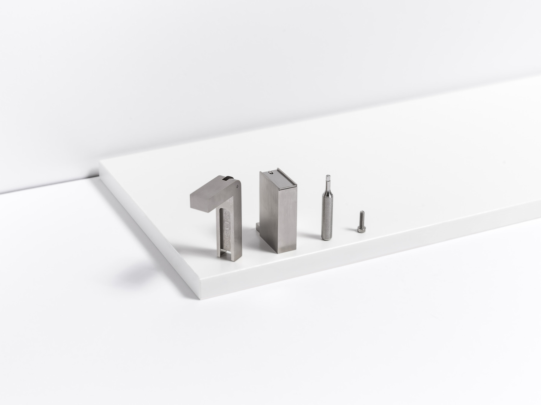A silver-toned KNNOX object and several components are arranged in a line across stepped white studio planes.